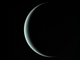 A thin aquamarine crescent of Uranus against a uniformly black background