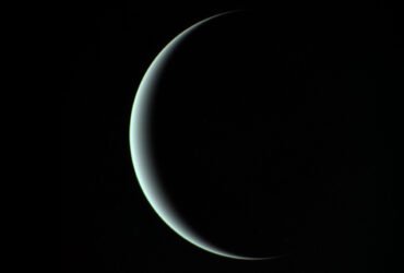 A thin aquamarine crescent of Uranus against a uniformly black background