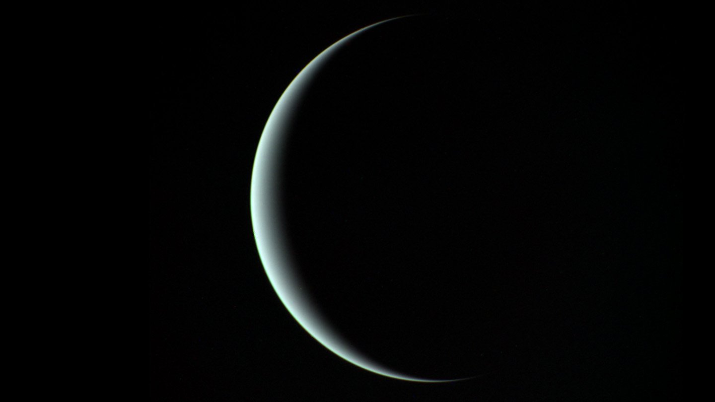 A thin aquamarine crescent of Uranus against a uniformly black background