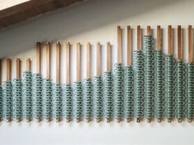 a wood and rope installation of sage green hues hangs on a wall