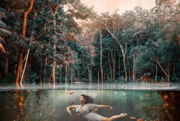Photograph of girl dancing underwater showing both the scenery above and below the water.