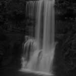a moody black and white image of a waterfall