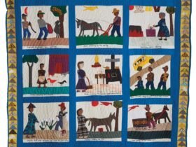 a pictorial quilt with nine frames showing people and animals in everyday activities, surrounded by a blue border and geometric patterns