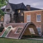 a public art piece in a a park featuring the facade of a London townhouse that appears to sit on the ground with its knees up