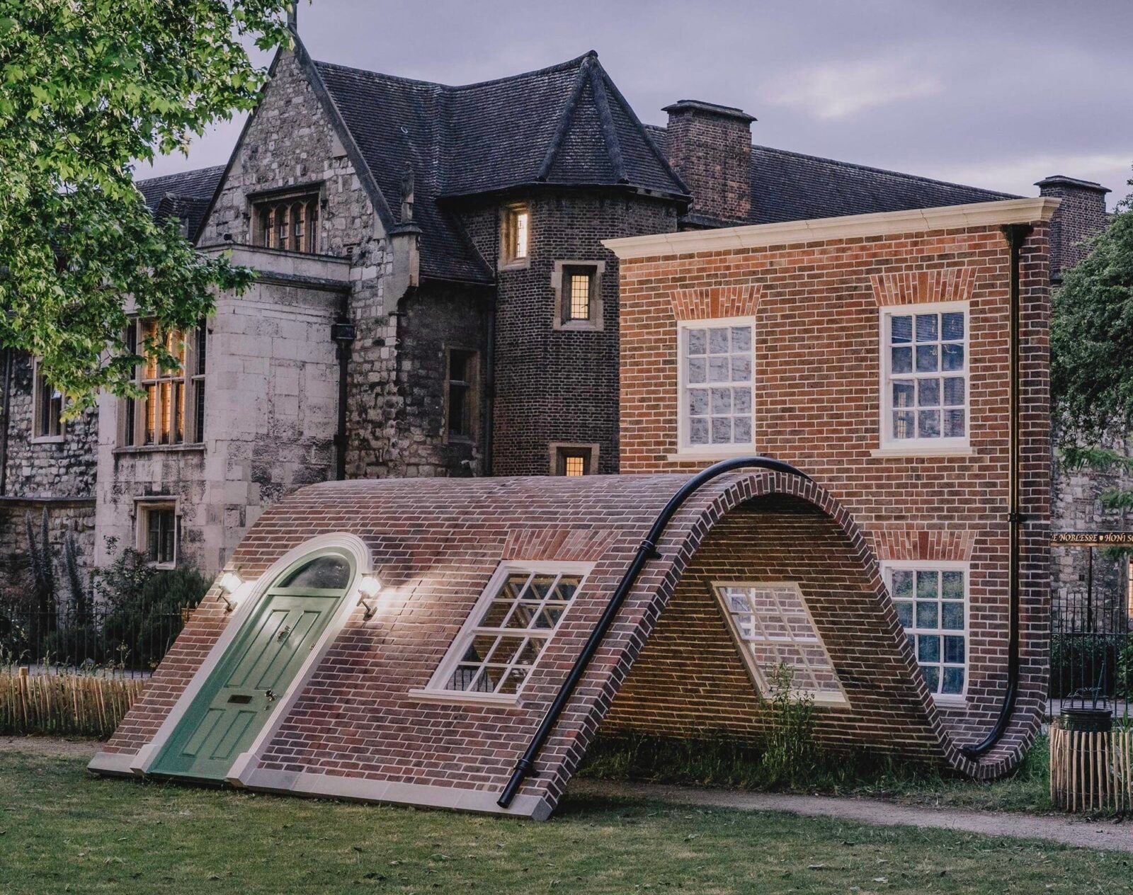 a public art piece in a a park featuring the facade of a London townhouse that appears to sit on the ground with its knees up