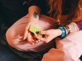 Description: A young woman sits on a comfortable couch, holding a blister pack of birth control pills. This candid shot captures a personal moment related to contraceptive use and hormone therapy, emphasizing the importance of reproductive health. Perfect for themes around women???s health, contraception, hormone therapy, and self-care, this image can be used to highlight modern health choices in a relaxed, home environment.