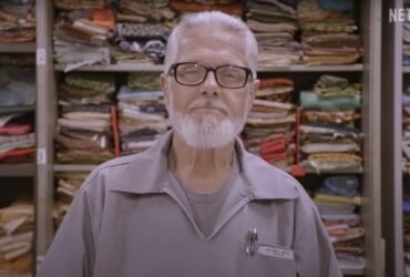 a man standing in front of shelves of fabric