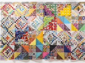 an artwork comprising cloth made from woven and connected pieces of plastic and paper, creating colorful patterns
