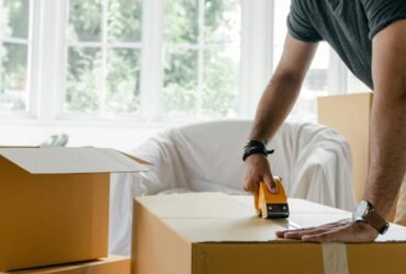 person taping a moving box