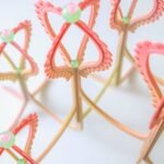 detail of a pink and yellow curved sculpture with scalloped edges