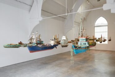 a collection of boats hangs in a gallery