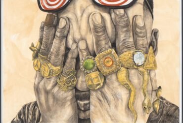 a man holds his hands over his eyes and each finger has a big gold ring with gems