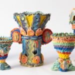 a series of five elaborate, multi-colored ceramic vases made with clay piped like frosting