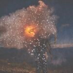 small holes pierce a dark photo of a person holding fire