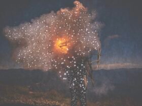small holes pierce a dark photo of a person holding fire