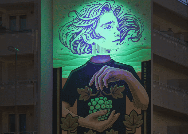 a gif exhibiting a glow-in-the-dark mural of a young figure holding a bunch of grapes