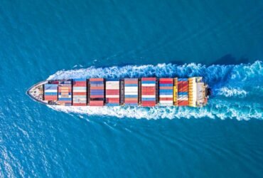 overhead shot as cargo ship sails on a blue sea.