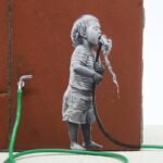 a detail of a child drinking from a green hose